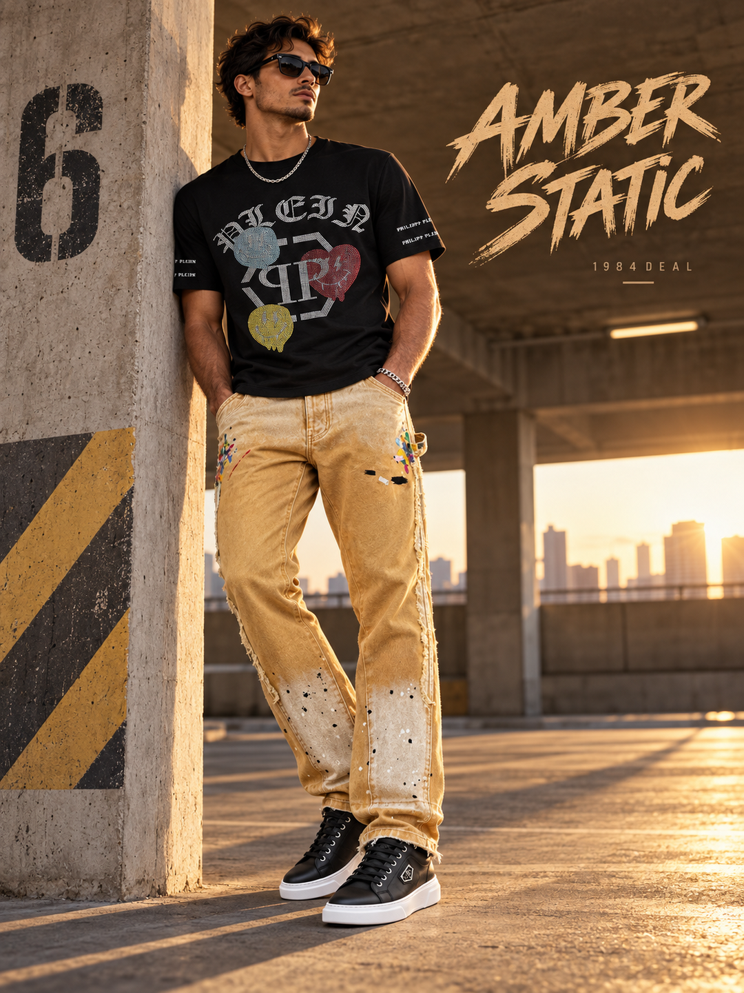 Adult man in a black graphic T-shirt, yellow paint-splatter jeans and black sneakers in a sunlit parking structure