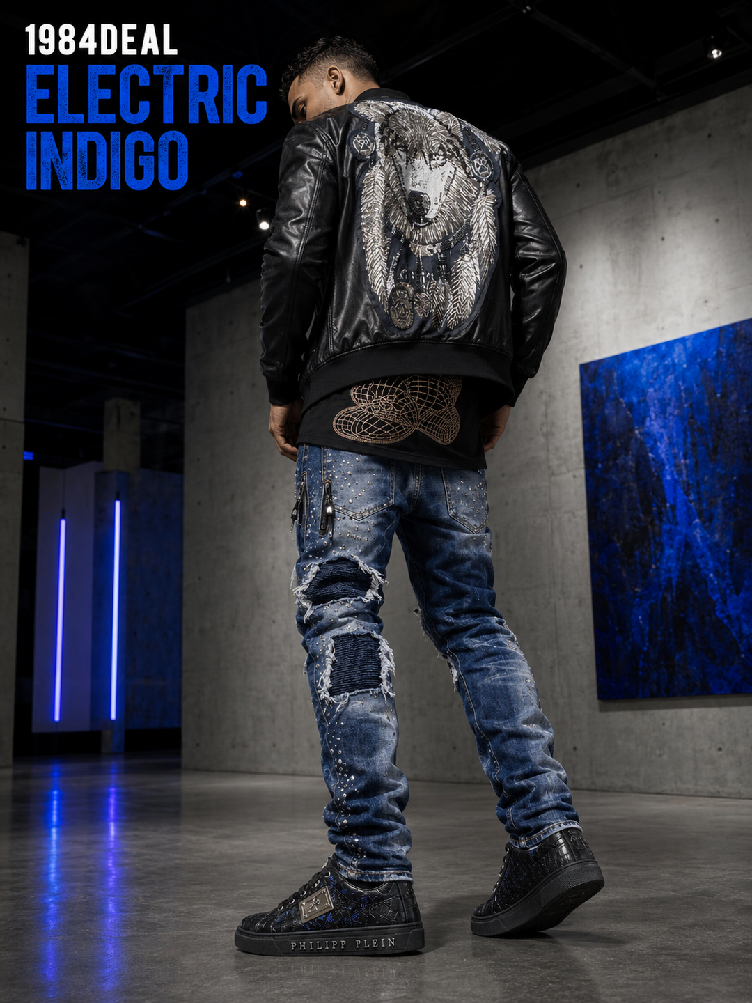 Man wearing a graphic black leather jacket, distressed blue jeans and black-blue sneakers