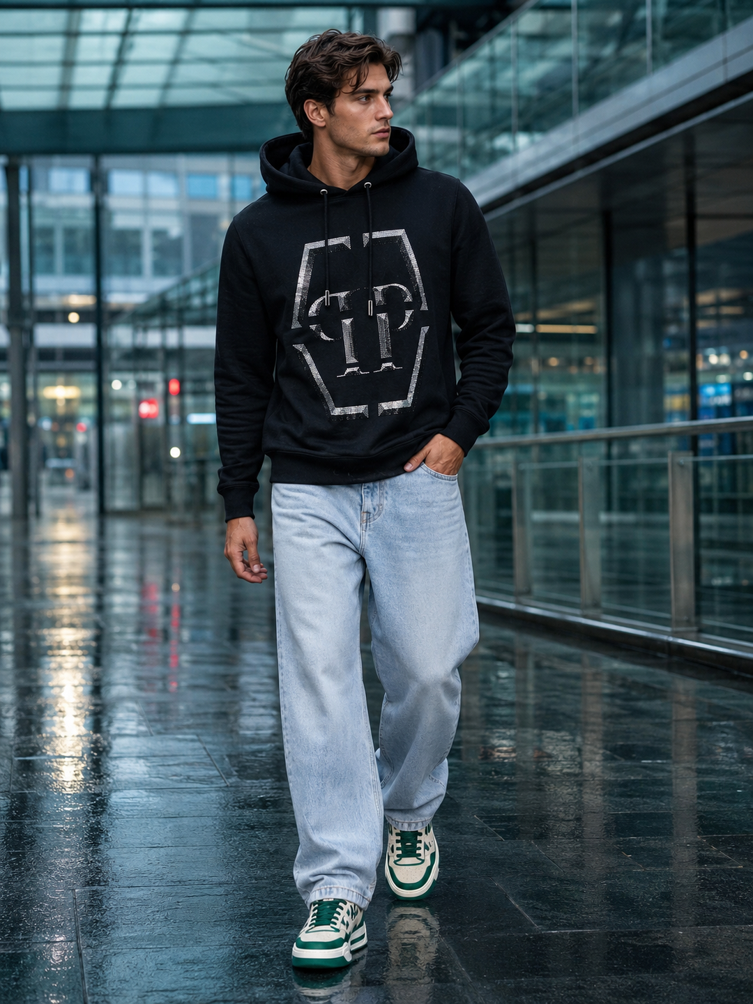 Man wearing a black graphic hoodie, light-wash jeans and cream-green sneakers