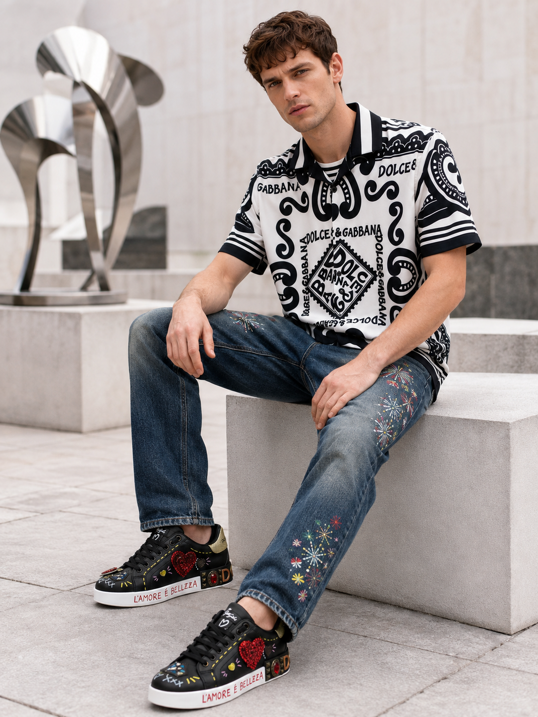 Male model in a white-black graphic shirt, dark blue jeans and black graphic sneakers