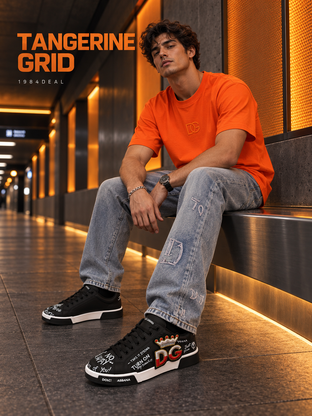 Adult man in an orange T-shirt, gray washed jeans and black graphic sneakers in an amber-lit transit passage
